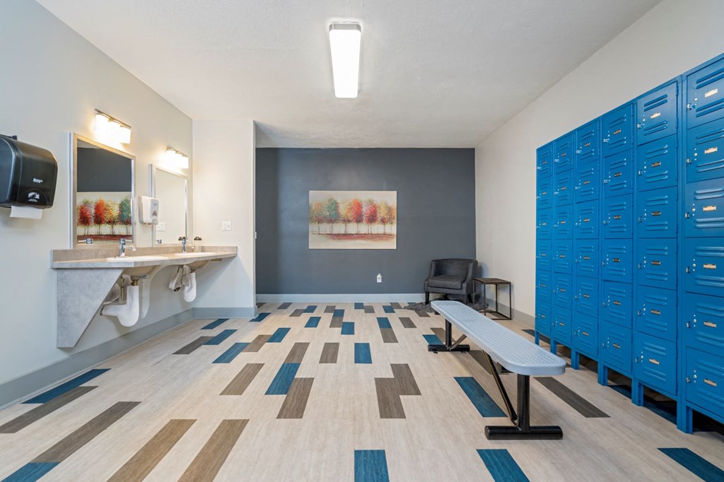 a locker room with blue lockers and a sink and a chair