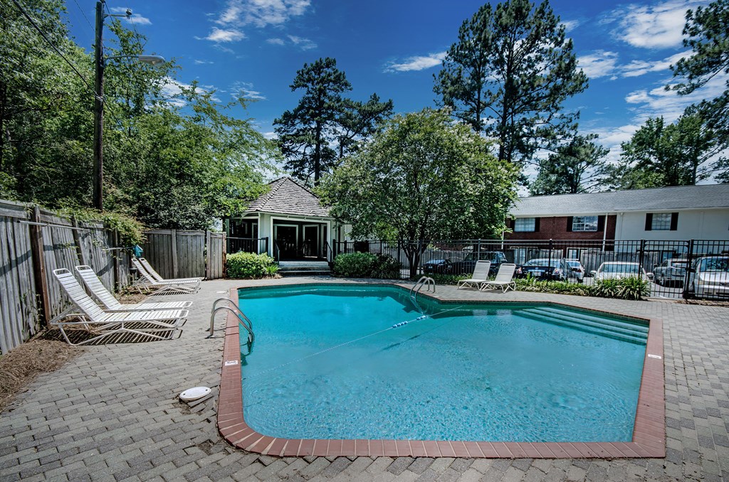 a pool with chairs and a house in the background