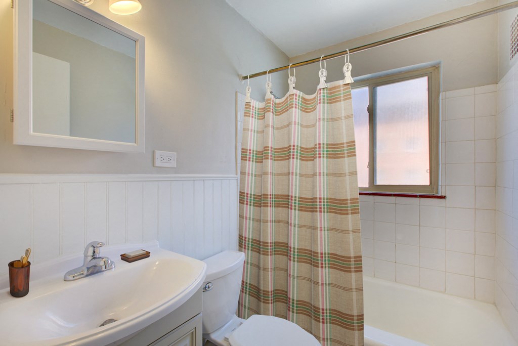a bathroom with a shower curtain and a toilet and a sink