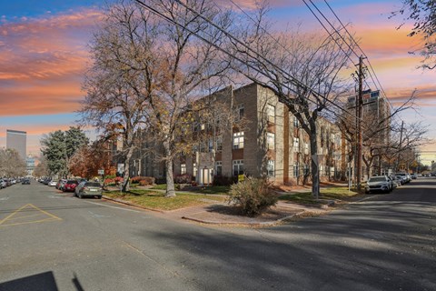 A street view of a residential area with cars parked on the side of the road.
