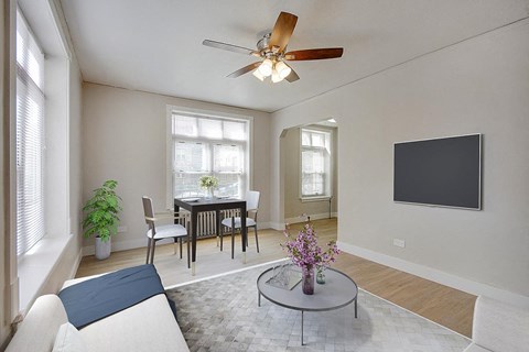 a living room with a table and a ceiling fan