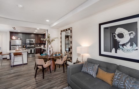 A modern living room with a grey couch and a dining table.