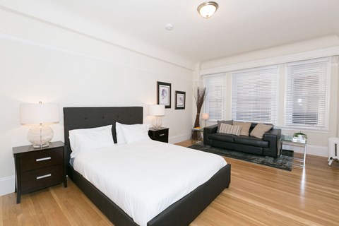 A bedroom with a large bed and a black couch.