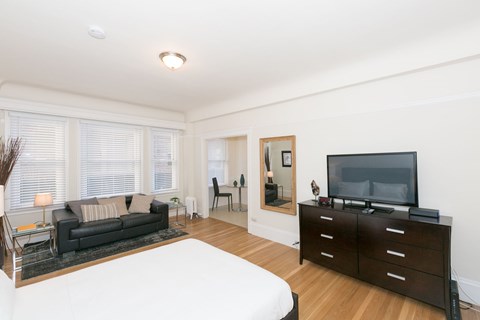A living room with a black couch and a television on a cabinet.