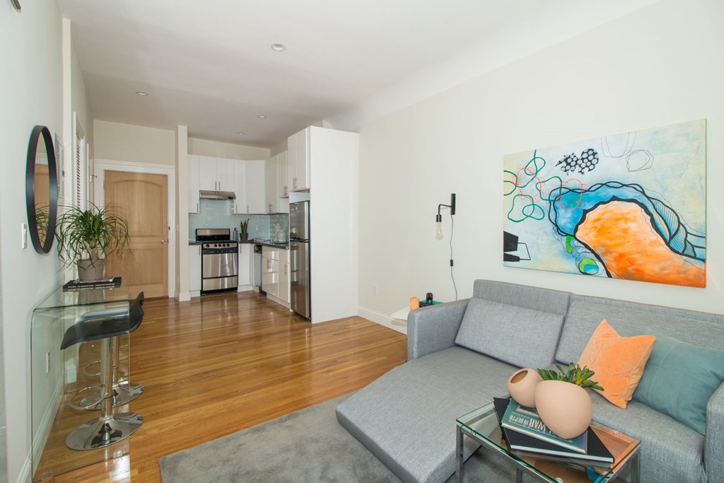 A living room with a grey couch and a painting on the wall.