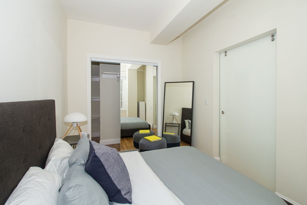 A bedroom with a bed, a dresser, a mirror, and a lamp.