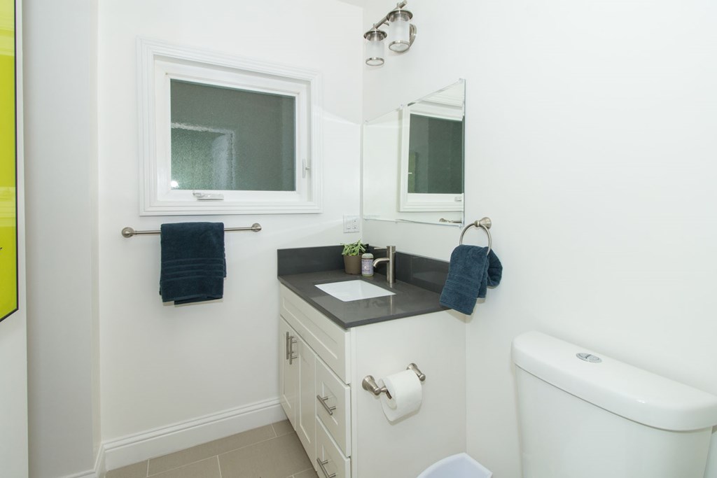 A white bathroom with a sink, mirror, and toilet.