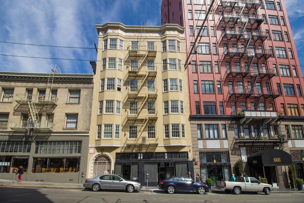 A row of buildings with cars parked in front.