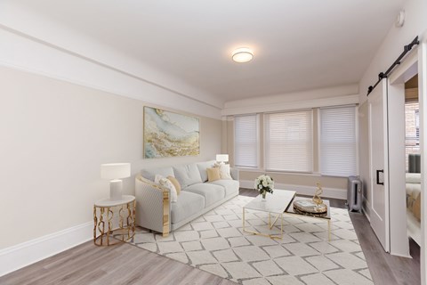 A living room with a white couch, a coffee table, and a painting on the wall.