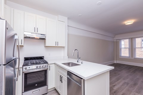 A kitchen with white cabinets and a stainless steel refrigerator.