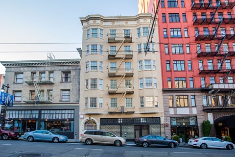 A row of buildings with cars parked in front.