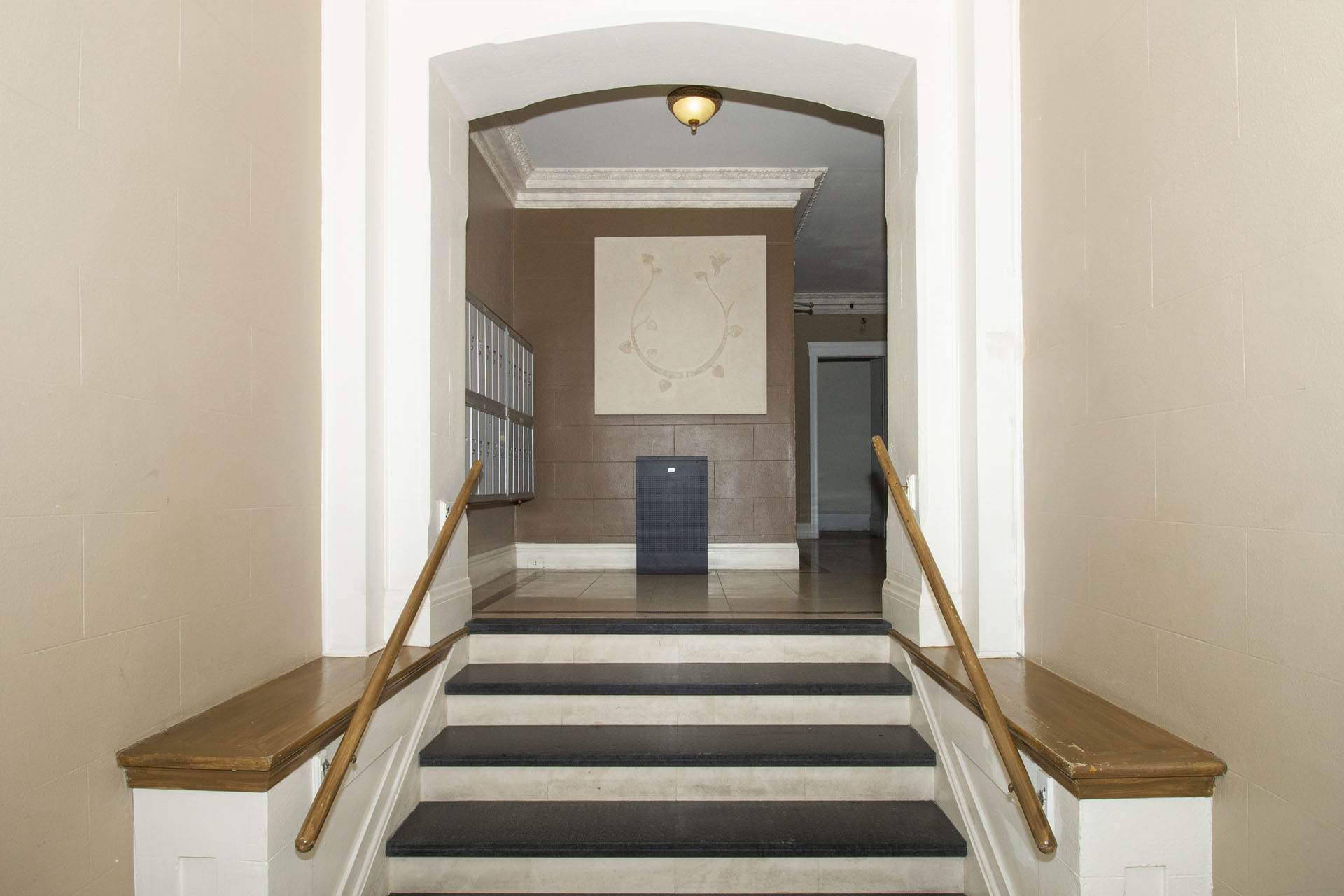 A hallway with a staircase and a clock on the wall.