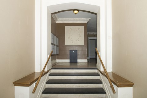 A hallway with a staircase and a clock on the wall.