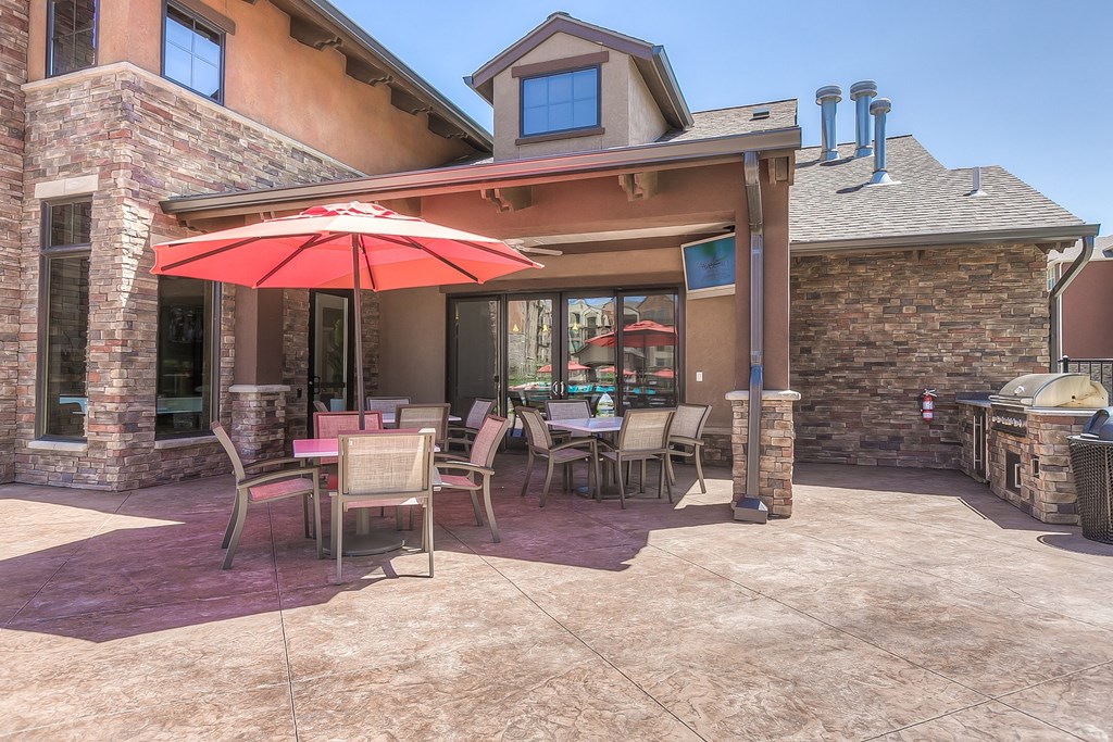 a patio with a grill and tables with umbrellas at EdgeWater at City Center, Lenexa, KS