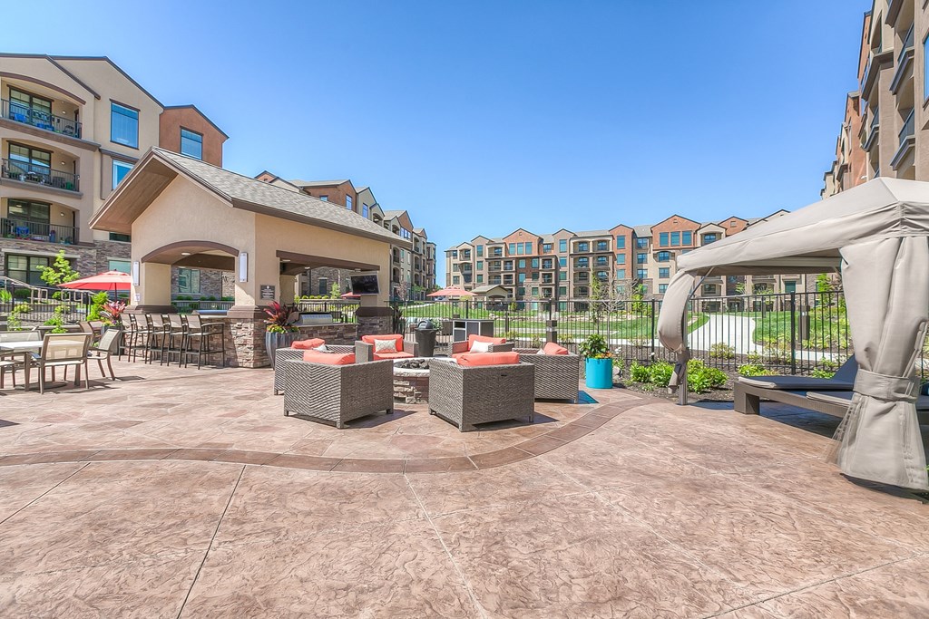 table and chair with grill and seating around a firepit with apartments in background  at EdgeWater at City Center, Kansas