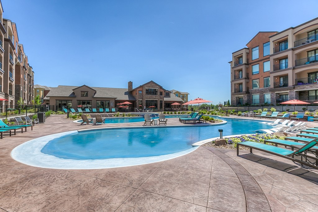 a swimming pool with chaise lounge chairs and a resort style building in the background  at EdgeWater at City Center, Kansas, 66219