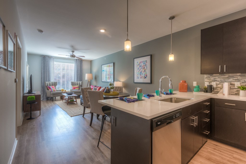 a kitchen with a large counter and a living room in the background  at EdgeWater at City Center, Lenexa, KS