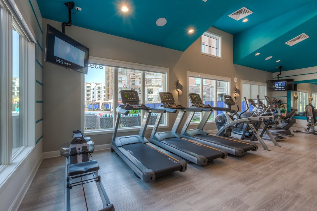a room filled with cardio equipment and a flat screen tv  at EdgeWater at City Center, Lenexa, 66219