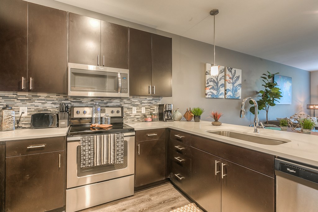 a kitchen with stainless steel appliances and white countertops a kitchen with stainless steel appliances and white countertops at EdgeWater at City Center, Lenexa, KS, 66219