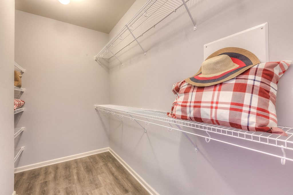 a closet with a shelf with a hat and pillows on it and a shelf  at Waterside Residences on Quivira, Lenexa, Kansas