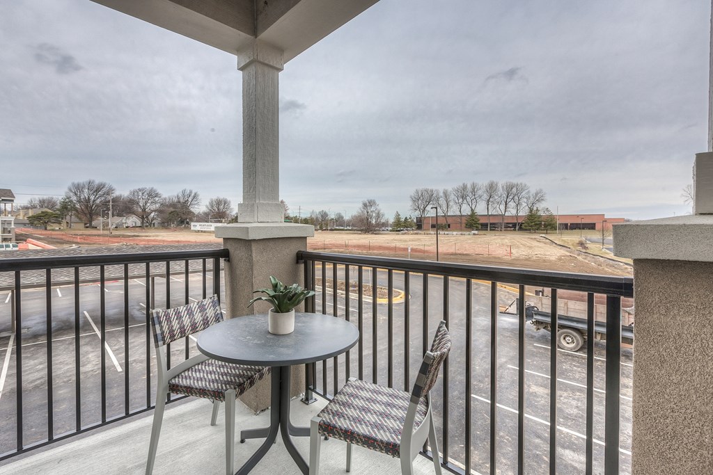 a balcony with a table and chairs and a view of a parking lot  at Waterside Residences on Quivira, Lenexa, 66215