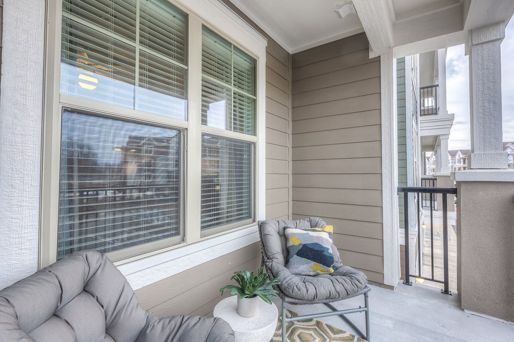 a covered porch with a chair and a window  at Waterside Residences on Quivira, Lenexa, KS, 66215