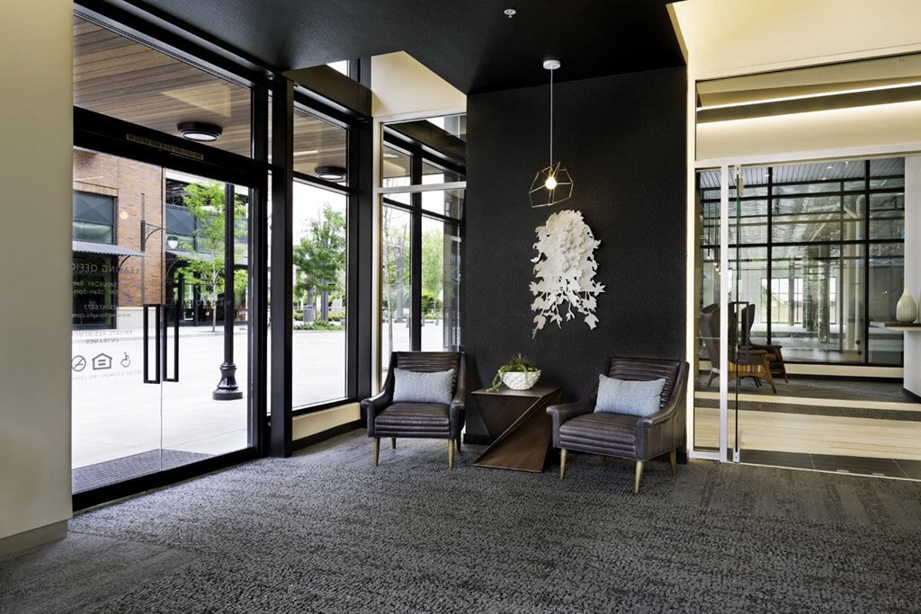 a lobby with two chairs and a table and glass doors