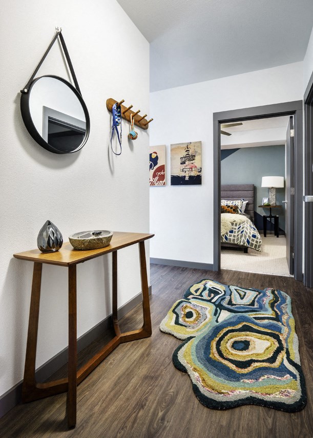a hallway with a mirror and a table with a rug