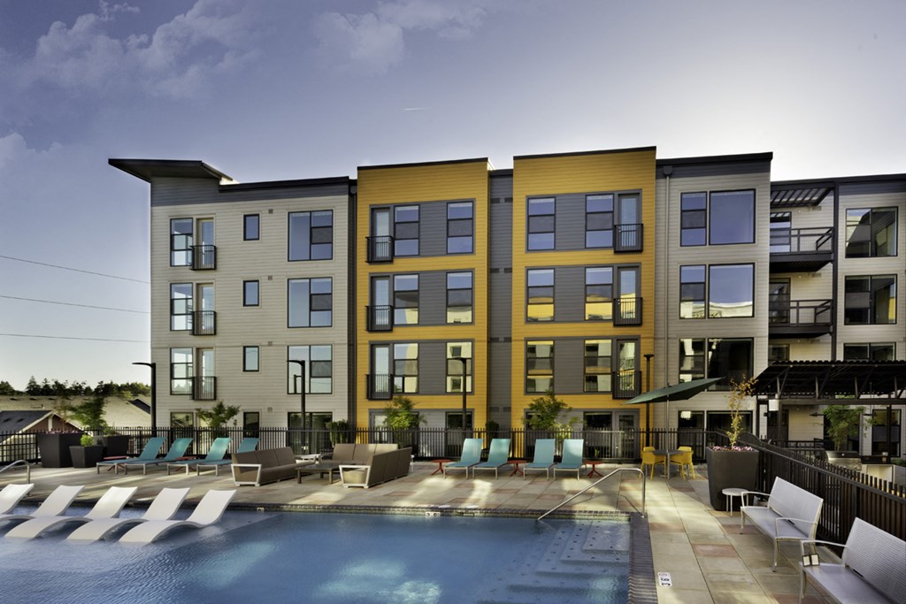 a building with a pool and chairs in front of it