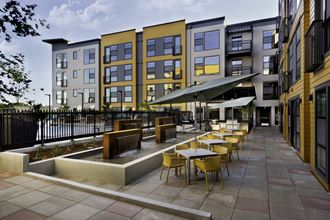 a rendering of a patio with tables and chairs in front of a building