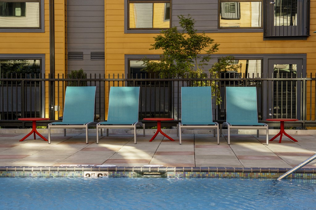 a row of blue and red chairs sitting next to a swimming pool