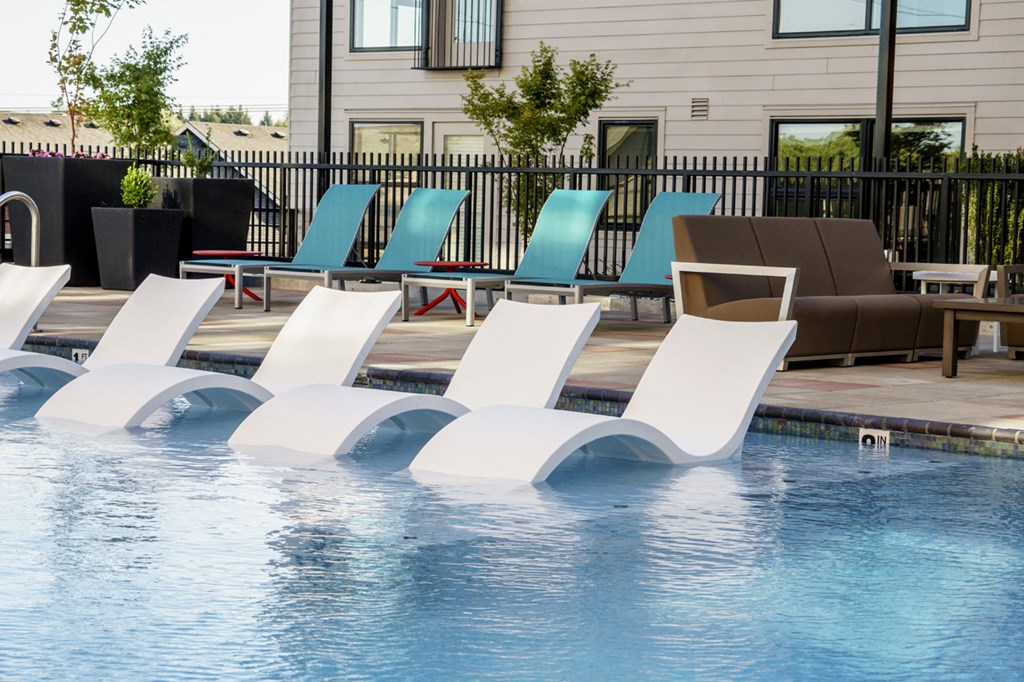 a group of white lounge chairs in a swimming pool