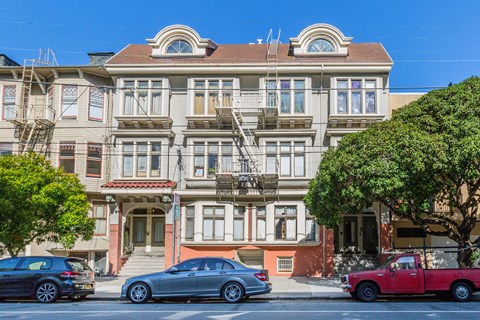 A row of houses with cars parked in front.