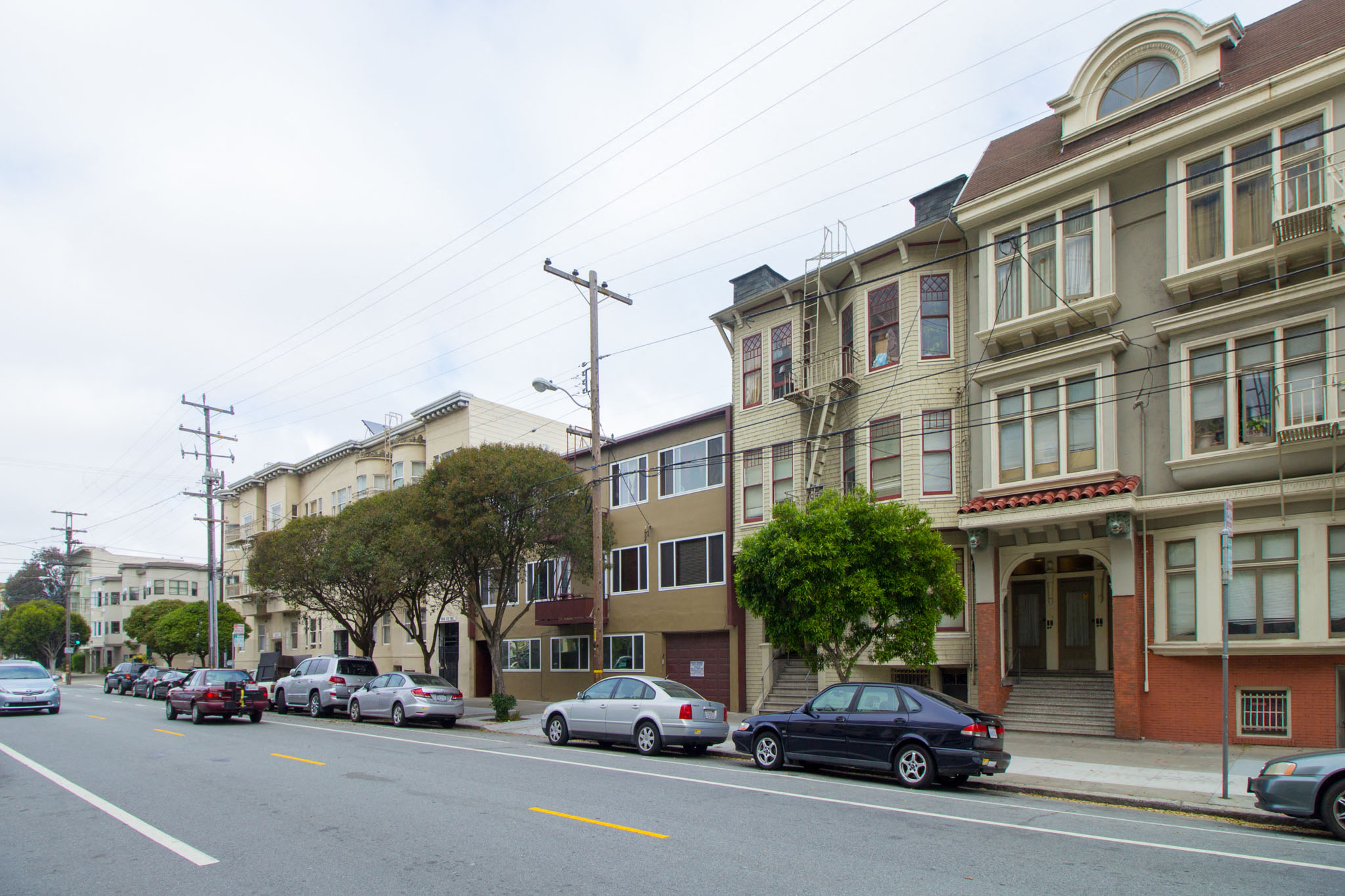 A street with cars parked on the side and buildings on the side.