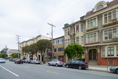A street with cars parked on the side and buildings on the side.