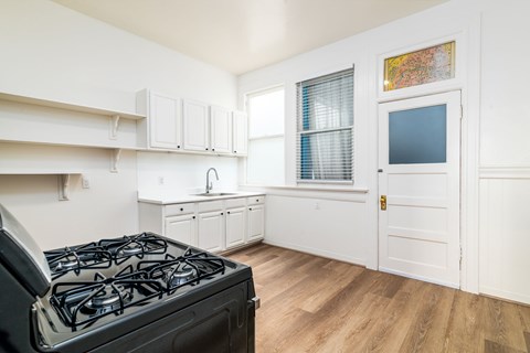 A kitchen with a black stove top oven and white cabinets.