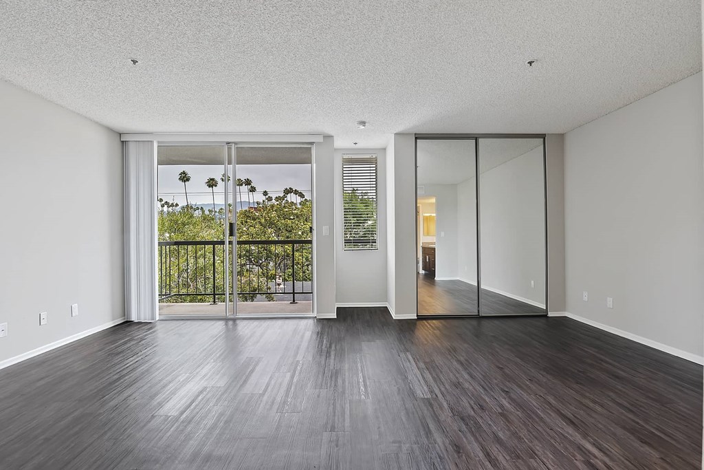 an empty living room with wood floors and a balcony