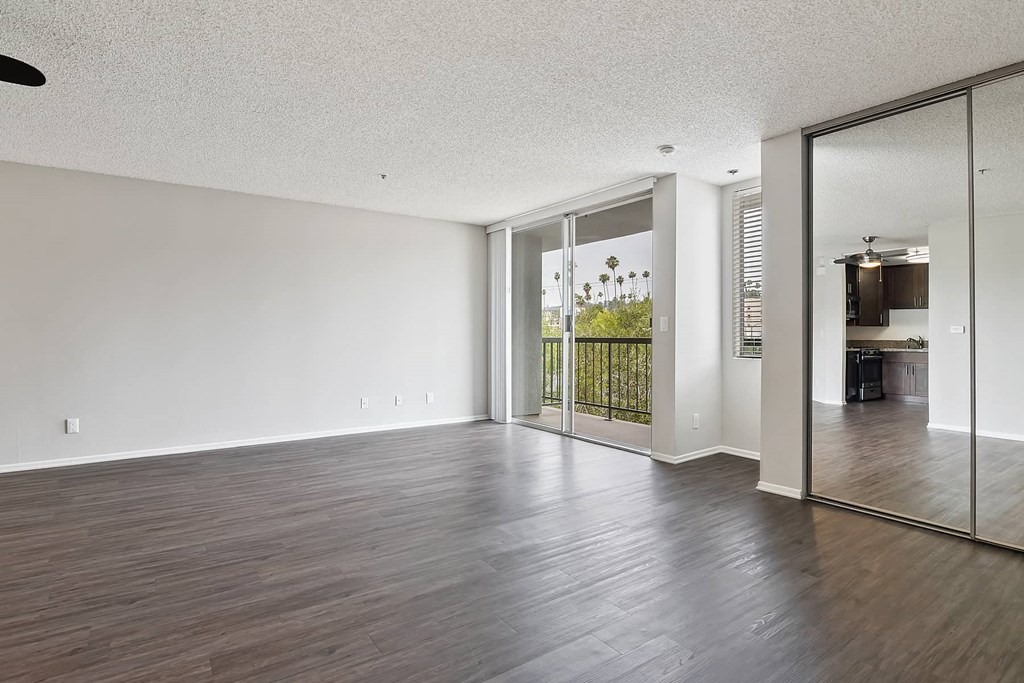 an empty living room with wood flooring and sliding glass doors to a balcony