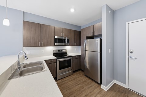 A kitchen with a sink, stove, oven, and refrigerator.