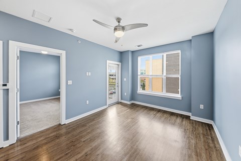 A room with a ceiling fan and a window with blinds.
