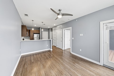 A room with a ceiling fan and wooden flooring.