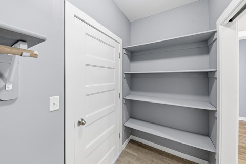 A white pantry with a door open to a white closet.