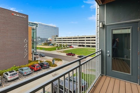 A balcony with a railing and a glass door leading to a building with the number 6457 on it.