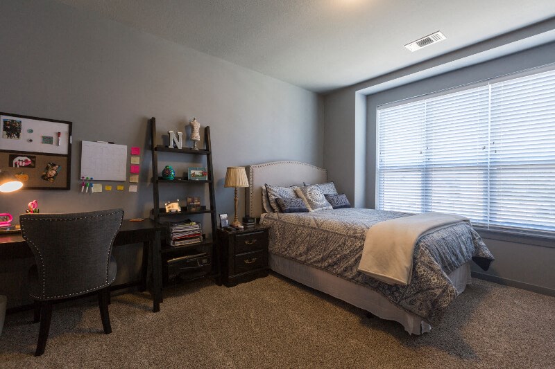 a bedroom with a bed and a desk and a large window