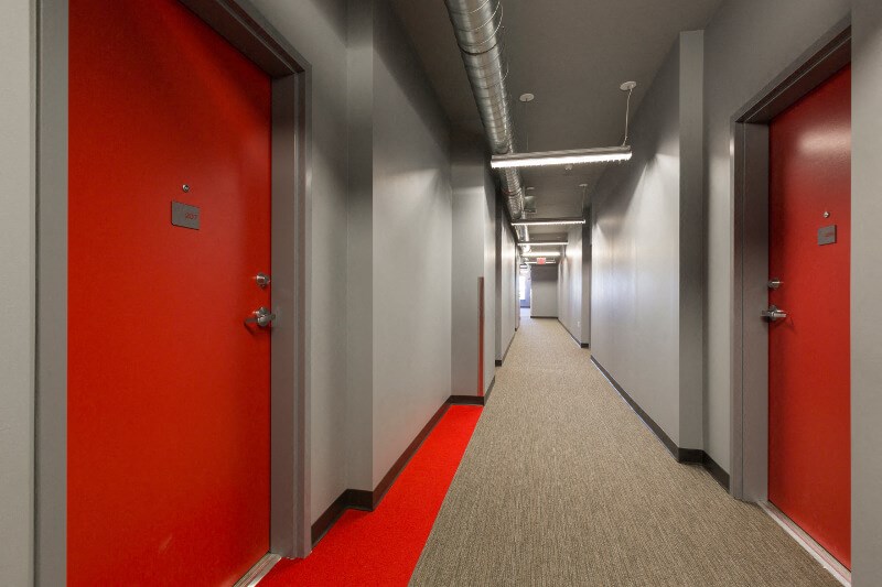 a hallway with red doors and gray walls and a red carpet on the floor