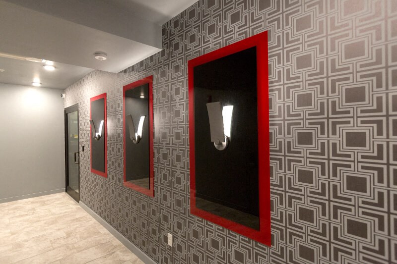 a hallway with three mirrors and red frames on a wall