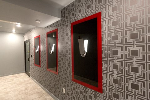a hallway with three mirrors and red frames on a wall
