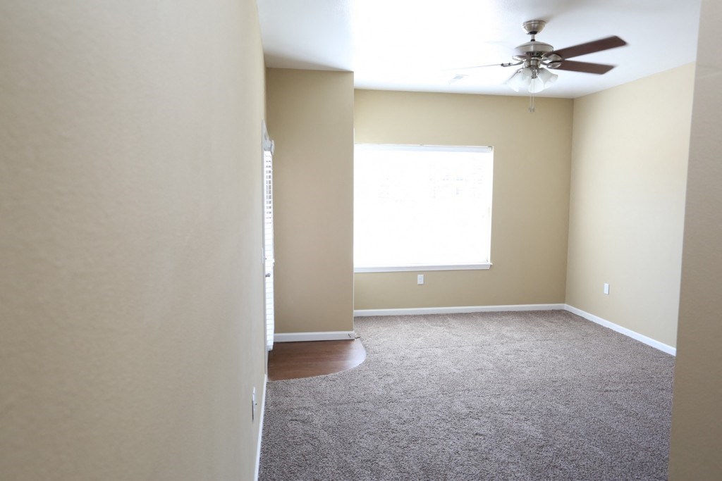 an empty room with a ceiling fan and a window