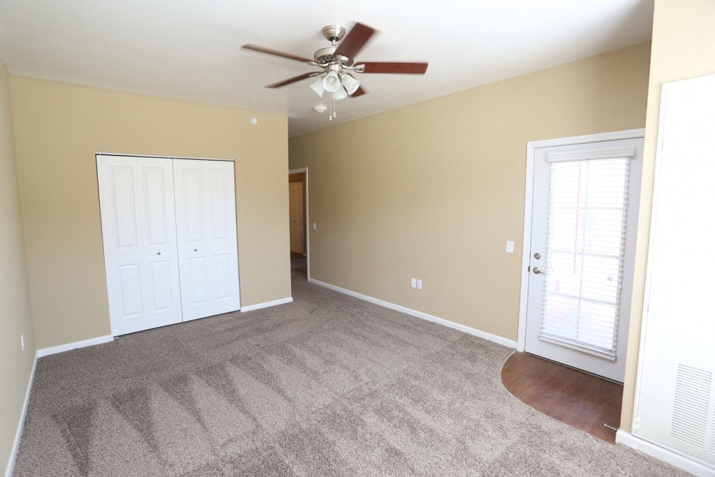 an empty living room with a ceiling fan