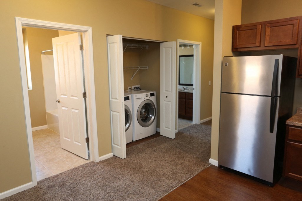 a laundry room with a washer and dryer and a stainless steel refrigerator